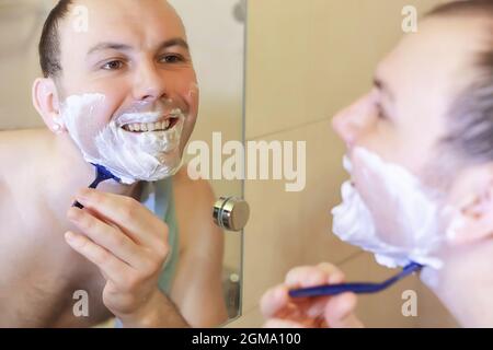 Ein Mann rasiert morgens vor der Arbeit im Bad Stockfoto