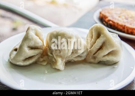 Khinkali oder xinkali oder hinkali- georgischer Knödel - in der Regel gefüllt mit Schwein oder Lamm oder Pilzen aus der Brühe auf einem Teller mit Khachapuri-Käse heiß Stockfoto