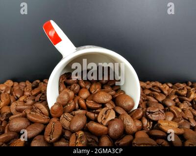 Nahaufnahme einer Tasse Kaffee mit gerösteten dunkelbraunen Kaffeebohnen Stockfoto