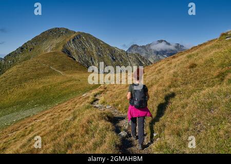 Frau Tourist mit Rucksack Wandern auf einem Weg in den felsigen Bergen, Spätsommer Stockfoto