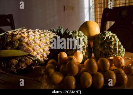 Verschiedene Früchte wie Ananas, malta, Orangen, Puddingäpfel, frische gelbe knusprige Datteln auf dem Esstisch für das Frühstück am Morgen. Esstisch im Innenbereich Stockfoto