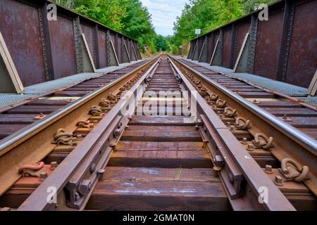 Eisenbahnschienen, die aus einer niedrigen Perspektive über eine rostige Eisenbahnbrücke in der Nähe von Washago Ontario aufgenommen wurden. Stockfoto