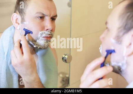 Ein Mann rasiert morgens vor der Arbeit im Bad Stockfoto