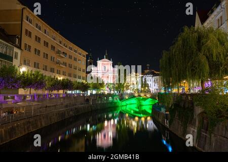 Preseren Platz mit Tromostovje Brücke auf Ljubljanica Fluss in der Nacht mit Stadtlichtern in Slowenien Ljubjana mit Cerkev Marijinega oznanjenja Kirche . Stockfoto