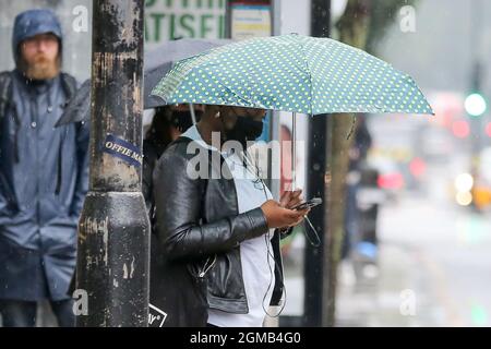 London, Großbritannien. September 2021. Eine Frau blickt während des Regens auf ihr Mobiltelefon. Kredit: SOPA Images Limited/Alamy Live Nachrichten Stockfoto