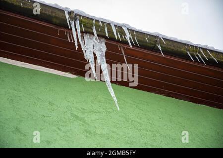 Eine Menge großer schöner Eiszapfen, die vom Dach hängen Stockfoto