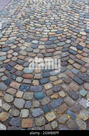 Dieses Bild zeigt eine Nahaufnahme eines alten Kopfsteinpflaster-Gehwegs auf einem europäischen Bürgersteig und Innenhof. Stockfoto