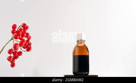 Rowan-Medizin auf einem weißen Hintergrund, ein Zweig aus roten Vogelbeeren mit einem Glas Medizin. Stockfoto