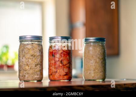 Sauerkraut, Dill-Kraut und Kimchi in Mason-Gläsern in der heimischen Küche Stockfoto
