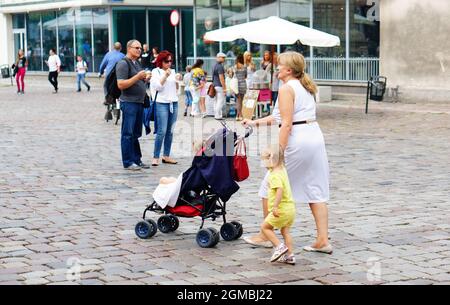 POZNAN, POLEN - 05. Februar 2016: Eine Frau, die mit einem Buggy läuft und die Hand eines Mädchens auf dem Stadtplatz in Poznan, Polen, hält Stockfoto