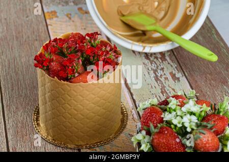 Dresskuchen, eingewickelt in eine strukturierte Schicht aus gesalzener Karamellschokolade. In der unteren Schüssel mit dem geschmolzenen Karamell. Stockfoto