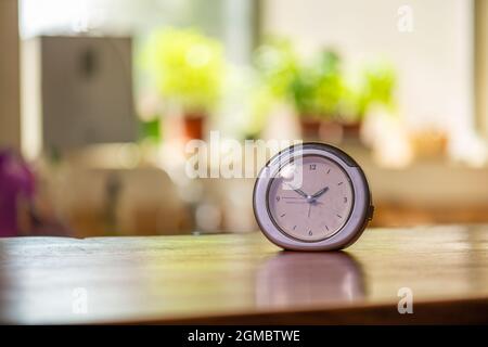 Uhr auf Holztheke in der Küche mit Fenster und Kräutern im Hintergrund Stockfoto