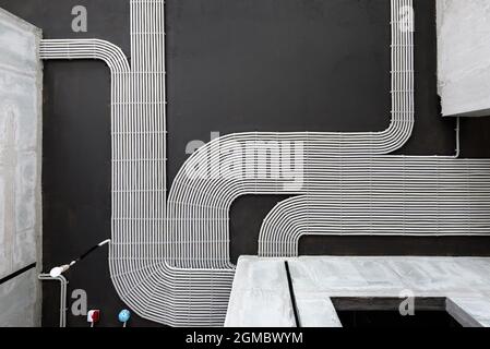 Elektrokabel und Rohre auf dem Hintergrund der Betondecke des Hauses, Kunststoffschläuche mit Drähten im leeren Raum. Leitungen von pvc-Leitungen nach professionellen Stockfoto