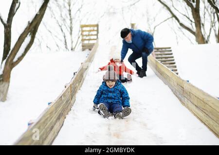 Kinder im Park im Winter. Kinder spielen mit Schnee auf dem Spielplatz. Sie Formen Schneemänner und rutschen Hügel hinunter. Stockfoto