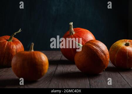 Fünf Kürbisse auf Holztisch mit dunklem Hintergrund. Stockfoto