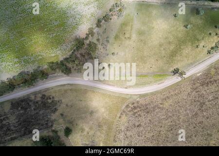 Unbefestigte Straße, die sich durch eine Buschlandschaft in einem Land schlengt, hochperspektivische Drohnenantenne Stockfoto