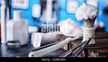 Rasierzubehör auf einem Hintergrund mit Holzstruktur. Werkzeuge. Einweg-Rasierer, Bürste, Rasierer mit Schaumgefahr. Stockfoto