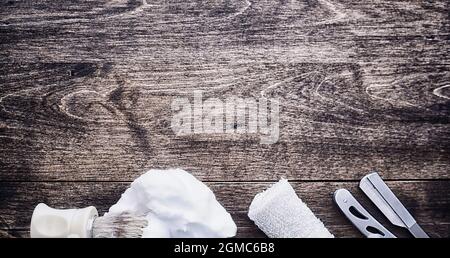 Rasierzubehör auf einem Hintergrund mit Holzstruktur. Werkzeuge. Einweg-Rasierer, Bürste, Rasierer mit Schaumgefahr. Stockfoto
