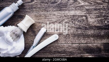 Rasierzubehör auf einem Hintergrund mit Holzstruktur. Werkzeuge. Einweg-Rasierer, Bürste, Rasierer mit Schaumgefahr. Stockfoto
