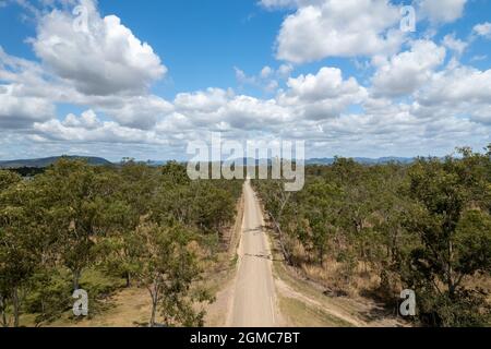 Gerade unbefestigte Straße durch eine Buschland-Landschaft, hochperspektivische Drohnenantenne Stockfoto