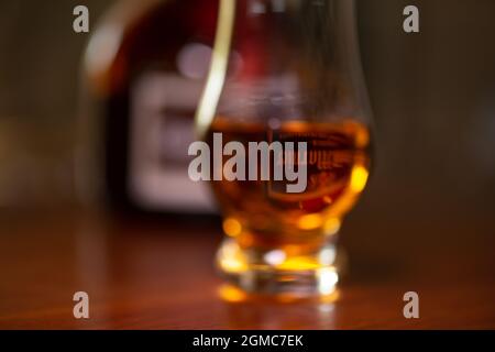 Verschwommenes, unscharfes Glas, gefüllt mit Grand Manier-Alkohol, was auf verschwommenes Sehen durch Betrunkenheit hinweist. Stockfoto