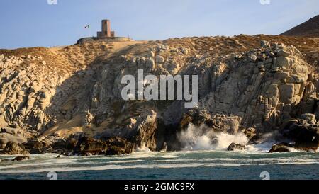 CABO SAN LUCAS, BAJA CALIFORNIA SUR, MEXIKO...RIESIGE WELLEN STÜRZEN ENTLANG DER ZERKLÜFTETEN PAZIFIKKÜSTE IN DER NÄHE DES ALTEN LEUCHTTURMS Stockfoto