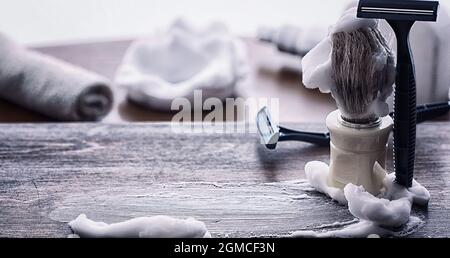 Rasierzubehör auf einem Hintergrund mit Holzstruktur. Werkzeuge. Einweg-Rasierer, Bürste, Rasierer mit Schaumgefahr. Stockfoto