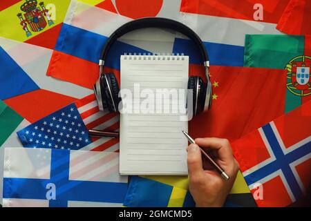 Fremdsprachen lernen. Audio-Sprachkurse. Hintergrund von Länderflaggen und Kopfhörern auf dem Tisch. Stockfoto