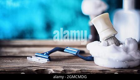 Rasierzubehör auf einem Hintergrund mit Holzstruktur. Werkzeuge. Einweg-Rasierer, Bürste, Rasierer mit Schaumgefahr. Stockfoto