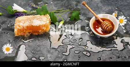 Honigwabe und Honig in Schale auf dunklem Hintergrund. Bio-Food-Konzept. Stockfoto