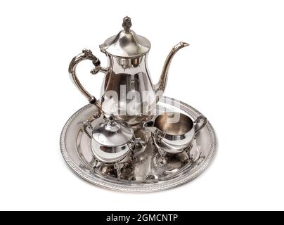 Isoliertes, kunstvolles 4-teiliges Teeset auf dem Tisch. Perspektivische Ansicht. Silberne oder versilberte Teekannen, Zuckerdose und Rahm- oder Milchkännchen. Zierbesteck t Stockfoto