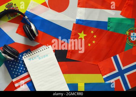 Fremdsprachen lernen. Audio-Sprachkurse. Hintergrund von Länderflaggen und Kopfhörern auf dem Tisch. Stockfoto