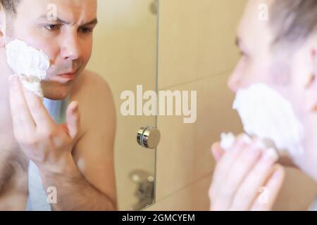 Ein Mann rasiert morgens vor der Arbeit im Bad Stockfoto