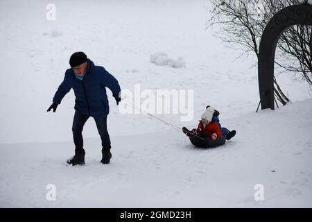 Kinder im Park im Winter. Kinder spielen mit Schnee auf dem Spielplatz. Sie Formen Schneemänner und rutschen Hügel hinunter. Stockfoto