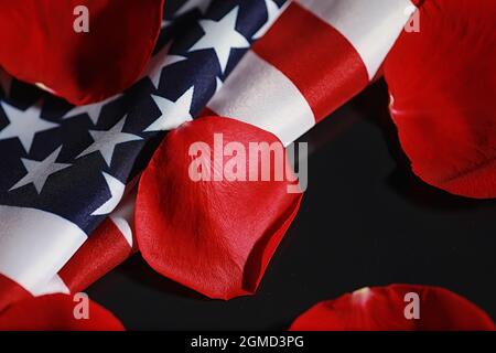 Amerikanische Flagge und Rosenblume auf dem Tisch. Symbol der Vereinigten Staaten von Amerika und rote Blütenblätter. Patriotismus und Erinnerung. Stockfoto