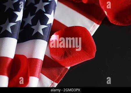 Amerikanische Flagge und Rosenblume auf dem Tisch. Symbol der Vereinigten Staaten von Amerika und rote Blütenblätter. Patriotismus und Erinnerung. Stockfoto