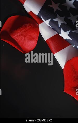 Amerikanische Flagge und Rosenblume auf dem Tisch. Symbol der Vereinigten Staaten von Amerika und rote Blütenblätter. Patriotismus und Erinnerung. Stockfoto