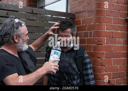 Melbourne, Australien. September 2021. Ein Anti-Blockierung-Protestler hilft einem anderen, der zuvor von der Polizei mit Pfeffer besprüht worden war. Quelle: Jay Kogler/Alamy Live News Stockfoto