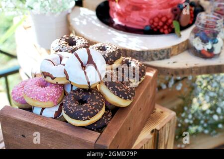Mini-Donuts in einer Holzkiste. Donuts in farbiger Glasur Stockfoto