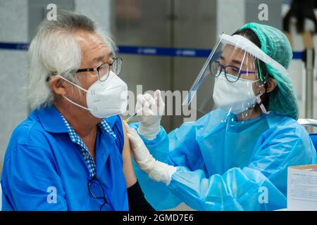 Bangkok, Thailand - September 17, 2021 : Asian Arzt oder Krankenschwester geben covid Antivirus-Impfstoff Schuss an ältere Mann Patient trägt Schutzmaske Gesicht Stockfoto