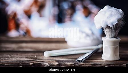 Rasierzubehör auf einem Hintergrund mit Holzstruktur. Werkzeuge. Einweg-Rasierer, Bürste, Rasierer mit Schaumgefahr. Stockfoto