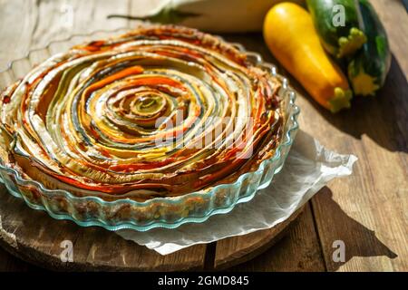 Gemüsekuchen mexikanische Sonne. Runde, offene Torte aus Zucchini, Auberginen und Karotten. Nahaufnahme von oben. Gesunde pflanzliche Lebensmittel. Vegetarismus. Spirale Stockfoto