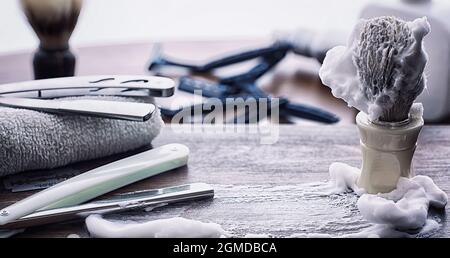 Rasierzubehör auf einem Hintergrund mit Holzstruktur. Werkzeuge. Einweg-Rasierer, Bürste, Rasierer mit Schaumgefahr. Stockfoto