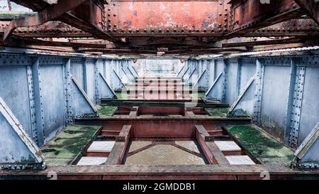 Verrostete Metallstruktur einer alten Eisenbahnbrücke, bedeckt mit Moos Stockfoto
