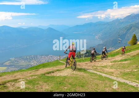 Verzasca, Schweiz - Juni 2021: Mountainbiker fahren vom Gipfel des Cardada-Cimetta-Gebirges in der Schweiz herunter. Schweizer Sessellift Skyline Stockfoto