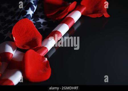 Amerikanische Flagge und Rosenblume auf dem Tisch. Symbol der Vereinigten Staaten von Amerika und rote Blütenblätter. Patriotismus und Erinnerung. Stockfoto