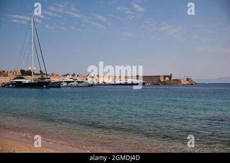 Rhodos, Griechenland - 25. Juli 2021: Griechischer Hafen mit Ägäis und einigen Booten während des sonnigen Sommertages. Rhodes Hafen mit wunderschönem Wasser. Stockfoto