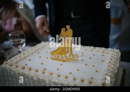 Hochzeitstorte mit goldenen Braut- und Bräutigam-Figuren darauf Stockfoto