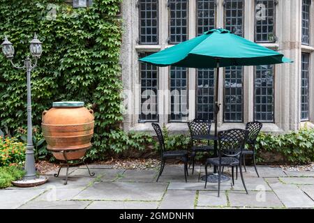 Schmiedeeiserne Terrasse und türkisner Regenschirm schaffen eine schöne Umgebung im formellen Garten Stockfoto