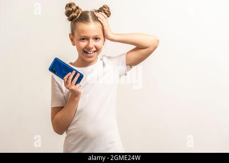 Ein Mädchen mit dunklen Haaren, um das Telefon zu halten und sich über den hellen Hintergrund zu wundern Stockfoto